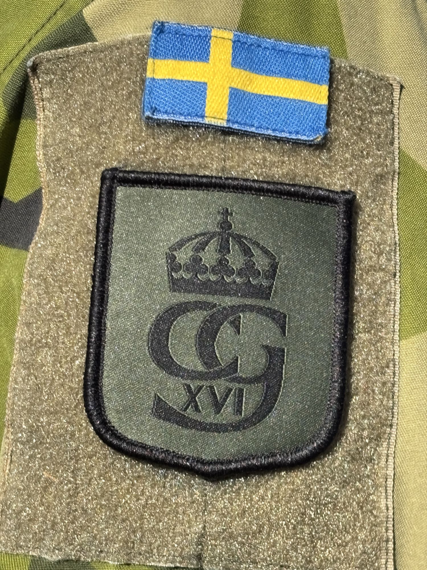 Tygmärken på en uniformsärm. Symbolen för Livgardet, kungens monogram samt en svensk flagga ovanför.